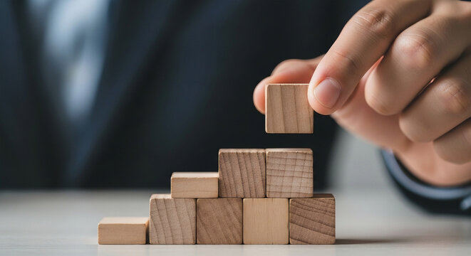 Hand stacking wooden blocks in ascending stair shape stairs building