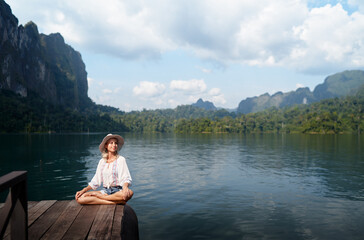 Fototapeta premium Woman Relaxing on a Dock by a Beautiful Khao Sok Lake with Scenic Views
