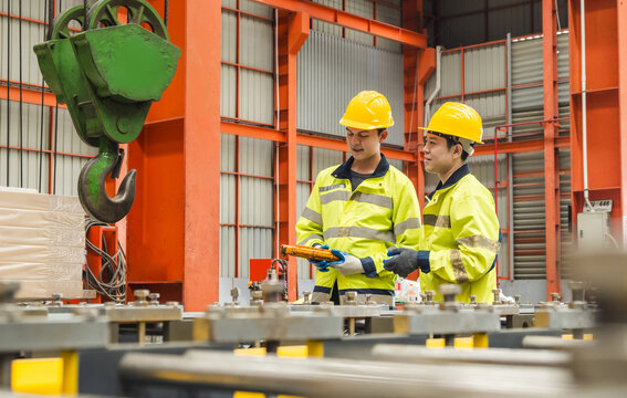 Leader manager talk work order staff male engineer technician team hard hat and uniform safety vest hand holding remote control overhead crane pick up heavy machine technology in industry factory - Powered by Adobe