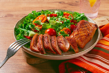 Delicious grilled duck breast served with fresh garden salad and cherry tomatoes at a rustic dining table
