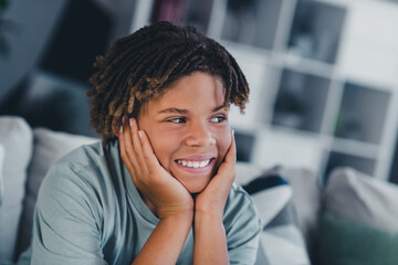 Smiling young boy relaxing at home with charming expression and happy mood enjoying leisure time in a cozy living room