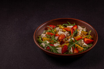 Fresh salad with strawberries, yellow tomatoes, arugula, and goat cheese in a rustic bowl