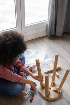 Woman assembling wooden stool on the floor