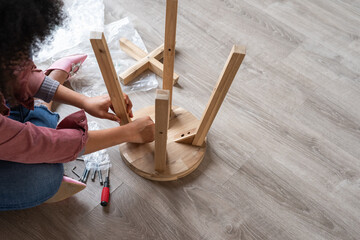 Anonymous woman putting together parts of new furniture