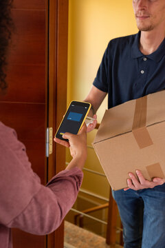 Delivery person taking payment for package from recipient at her home