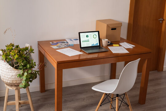 Laptop with financial data on screen on wooden table