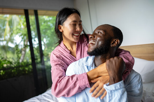 Young diverse multiethnic couple moving in new home. Couple is having fun in new house at moving day