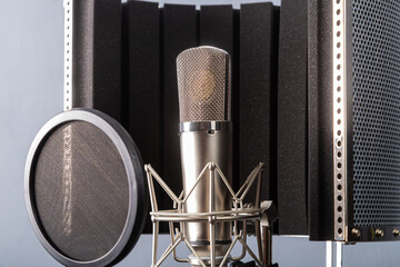 Studio microphone on a holder with a pop filter on a gray background in a recording studio