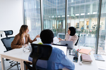Group of investors discussing projects sitting at one desk in office