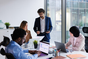Manager with tablet in hands conducting staff meeting at office