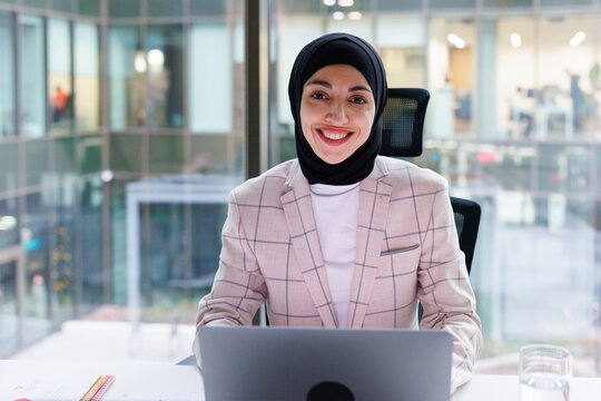 Portrait of muslim data analyst sitting in front of laptop at office