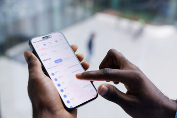 Closeup of black man tapping screen of smartphone to check data