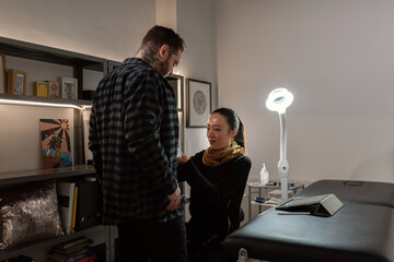 Tattoo artist working with client at studio