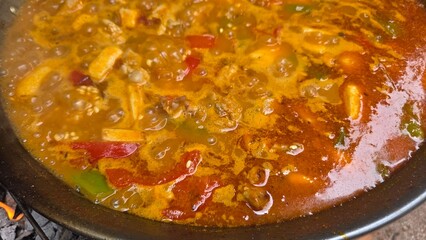 Traditional spanish paella simmering with vegetables and seafood for culinary delight. Typical cuisine of Spain. Valencian cuisine. Stage of cooking paella. Ingredients for paella