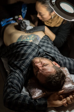 Man feeling pain while getting tattoo