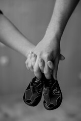 Couple holding baby shoes in black and white