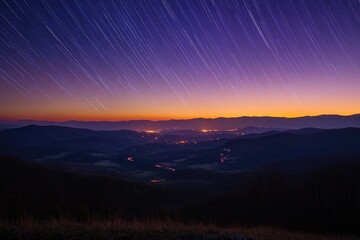 Obraz premium Star trails over a valley at sunset, showcasing a breathtaking panorama of mountains and lights.