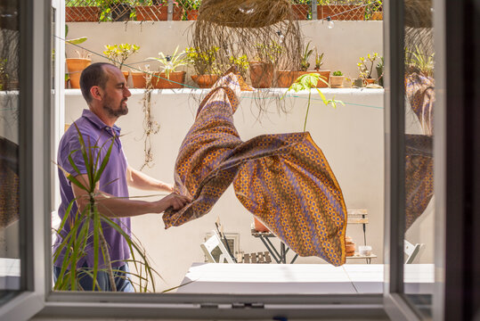 Man setting outdoor patio table with tablecloth