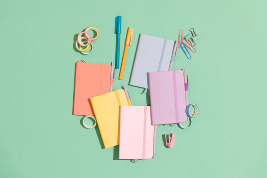 Pastel colored notebooks on a green background