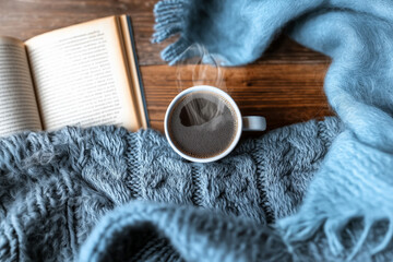 cup of coffee on wooden table next to a reading book