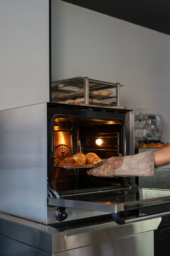 Baker Removing Freshly Baked Croissants From Oven in Bakery