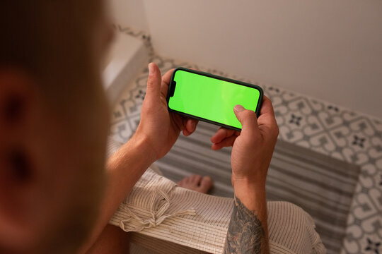 Man playing on his smartphone with green screen