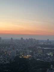 Obraz premium Tokyo skyline at dusk with Shinjuku skyscrapers glowing under a vibrant sunset sky, city lights beginning to twinkle over Japan’s bustling urban landscape