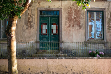 Old house facade with weathered walls, green door, and windows