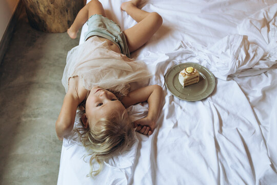 Birthday Bliss: Girl Lying in Bed Beside Cake