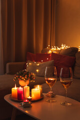 Cozy evening scene with candles, wine glasses and warm lighting.