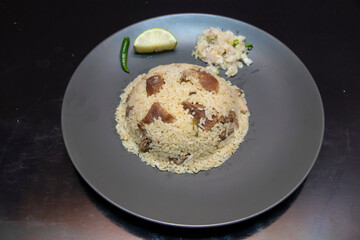 Beef Tehri Rice on Grey Plate with Lemon, Green Chili, and Salad top view of South Asian Dish