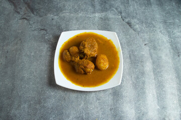 Traditional chicken curry with boiled egg in spicy gravy served on white plate top view