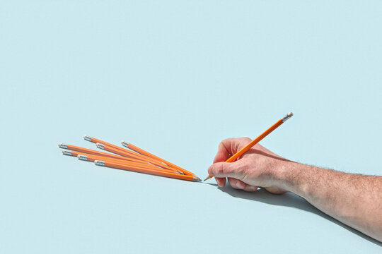 Hand arranging orange pencils in radiating pattern