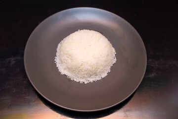 Steamed White Plain Rice Served on Dark Plate over Wooden Background top view of Traditional Asian Food