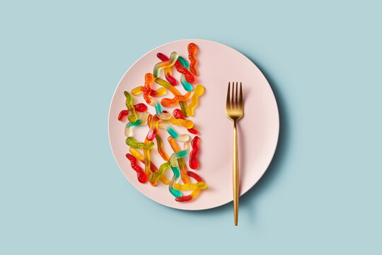 Gummy worms on plate with fork and sugar theme