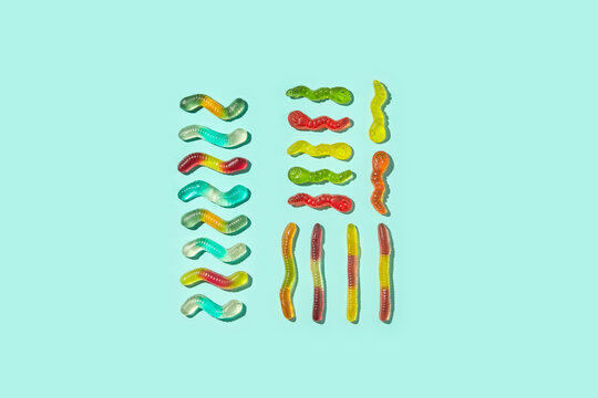Assorted gummy worms lined up on cyan background