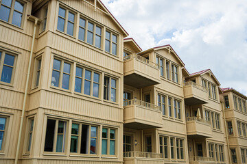 Beige wooden apartment buildings under cloudy sky.