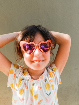 Happy Child in Heart Sunglasses with wonderful toothless smile.
