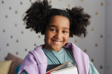 Smiling black student holding books and a tablet is ready for school