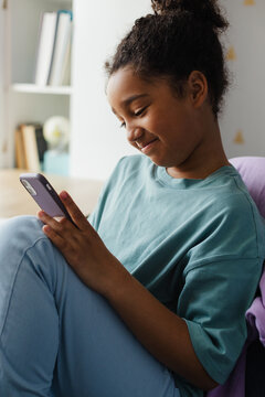 Smiling girl scrolling smartphone at home
