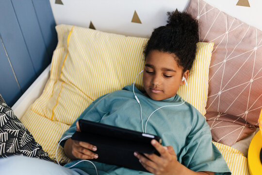 Black girl using tablet in bed watching videos