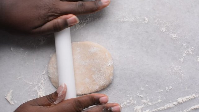 Overhead view of paratha dough being rolled out, top view of flaky flatbread dough, process of making paratha