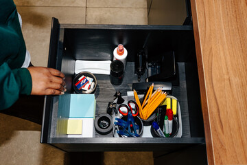 Hand of person opening office drawer with stationery supplies