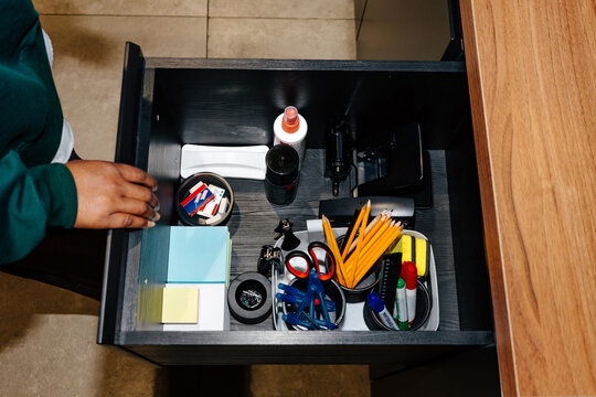 Hand of person opening office drawer with stationery supplies