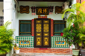 Chinese doorway with gold accents and tiled colonial walls