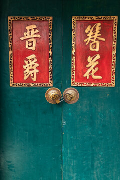 Green temple door with red Chinese calligraphy panels