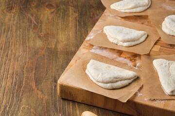 Step by step preparation of steamed bao buns with chicken, fresh cucumber and carrot filling on a wooden background. Rolling out the dough to make buns.