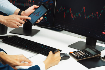 Cropped businessman checking on smartphone with woman investor taking note on paper with online website program application of dynamic stock market on screen at home office at back side. Infobahn.