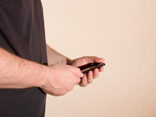 A man with a mobile phone in his hands is looking at something on the internet