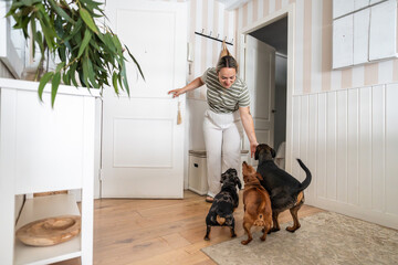 Happy woman arriving home and greeting her three dogs